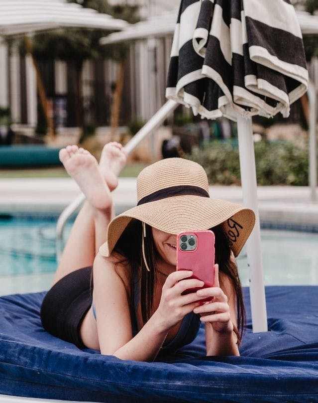 Girl by the pool looking at her phone - Elysian Living